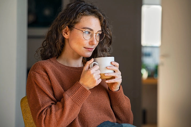 Frau hält eine Tasse Tee in den Händen und genießt eine ruhige Pause