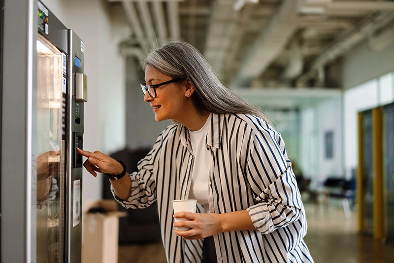 Frau bedient einen Getränkeautomaten in einem modernen Büro